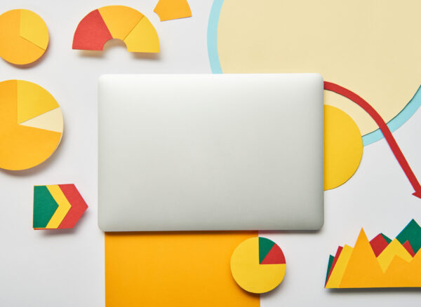 top view of laptop and paper charts and graph, pointers, sheet of paper on white background