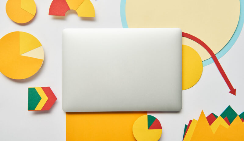 top view of laptop and paper charts and graph, pointers, sheet of paper on white background