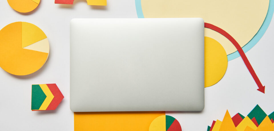 top view of laptop and paper charts and graph, pointers, sheet of paper on white background