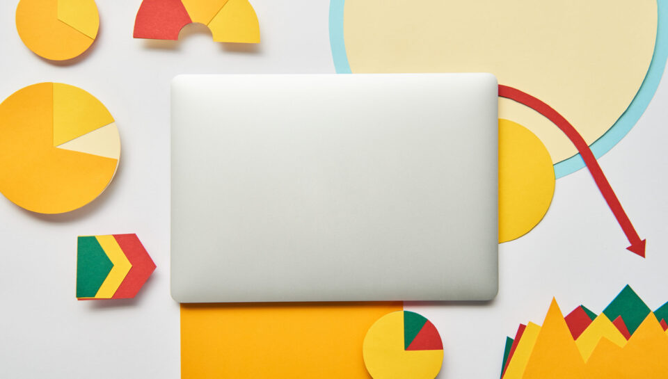 top view of laptop and paper charts and graph, pointers, sheet of paper on white background